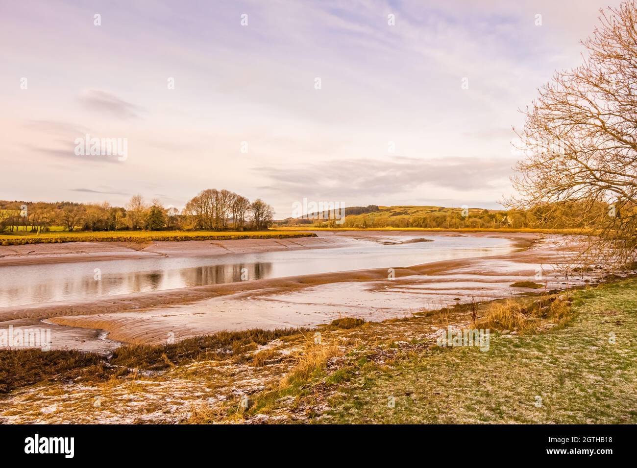 Mudflats con neve e gelo a terra, sull'estuario del fiume Dee a Kirkcudbright al tramonto in inverno, Dumfries e Galloway, Scozia Foto Stock