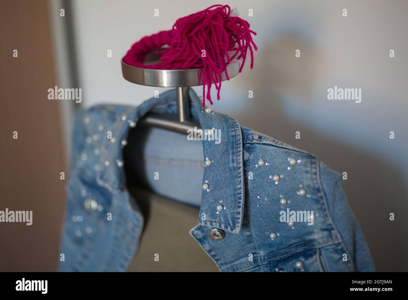 Giacca in jeans con biglie bianche e pantaloni beige che si aggancia su un  rack in metallo Foto stock - Alamy