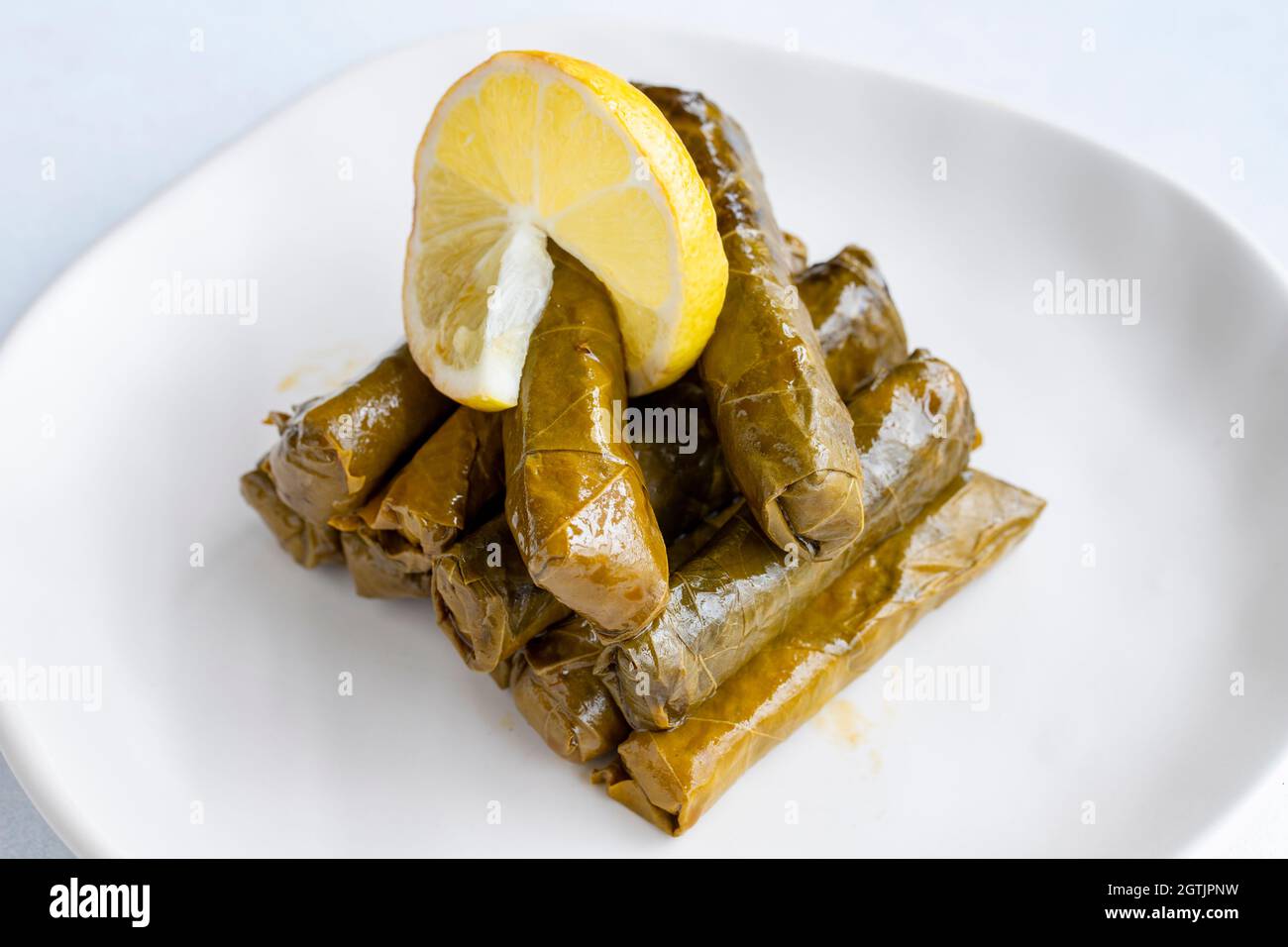 Foglie ripiene di olio d'oliva su sfondo bianco. Il gusto tradizionale della cucina turca. Nome locale zeytinyagli yaprak sarma Foto Stock