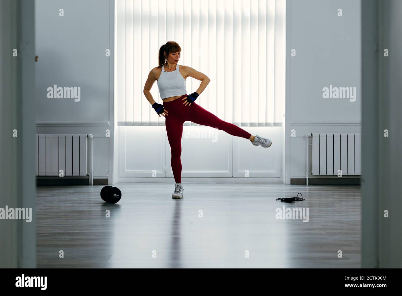 Fit Woman che si esercita con le braccia sui fianchi sotto Una finestra grande. Concetto di sport e training indoor. Foto Stock