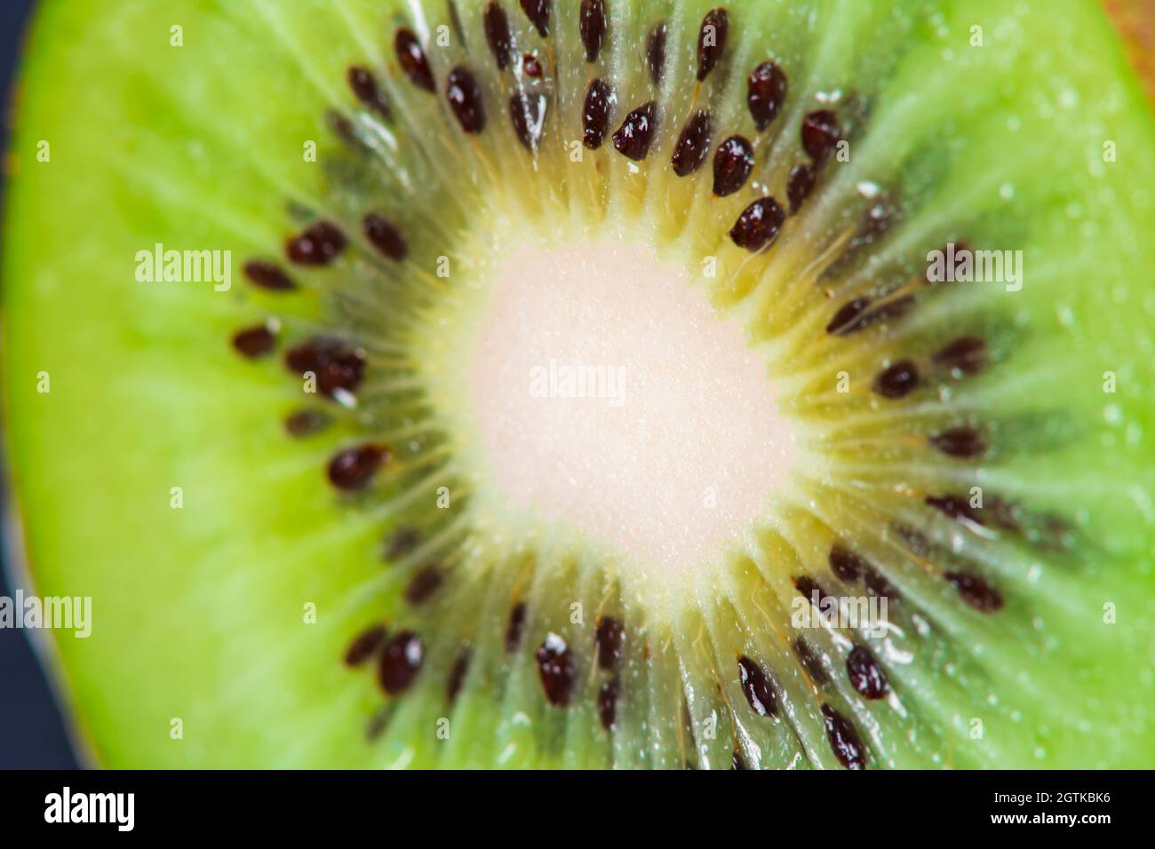 Macro frutta: Primo piano estremo di un kiwi maturo, fondo nero, formato orizzontale Foto Stock