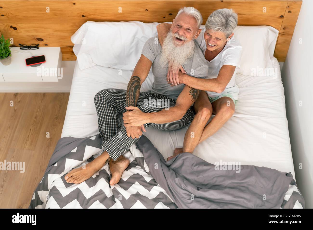 Coppia anziana felice sorridendo insieme a letto - persone mature Hipster che hanno momenti teneri in camera da letto - stile di vita anziano e concetto di rapporto d'amore Foto Stock