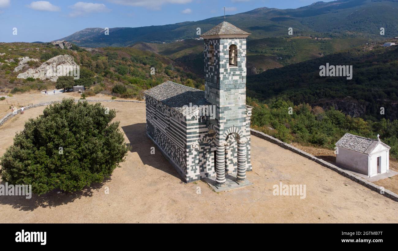 Veduta aerea della chiesa di San Michele di Murato in Corsica Settentrionale, Francia - chiesa in pietra policromica con un campanile verde e bianco nel moun Foto Stock