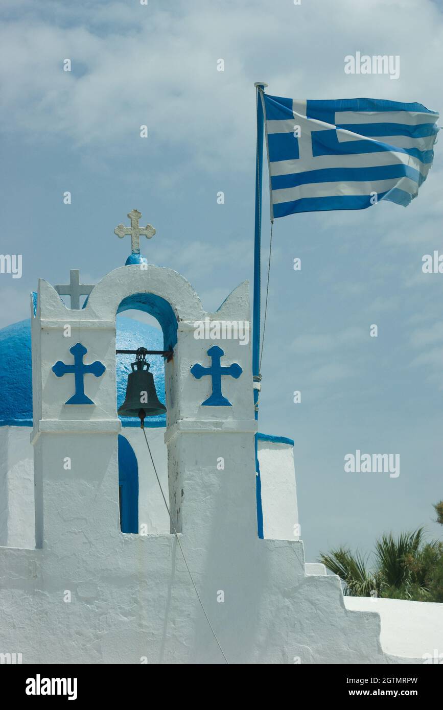 Isola di Paros Grecia. Piccola cappella affascinante. Colpo verticale di campanile con bandiera greca. Spazio di copia. Foto Stock