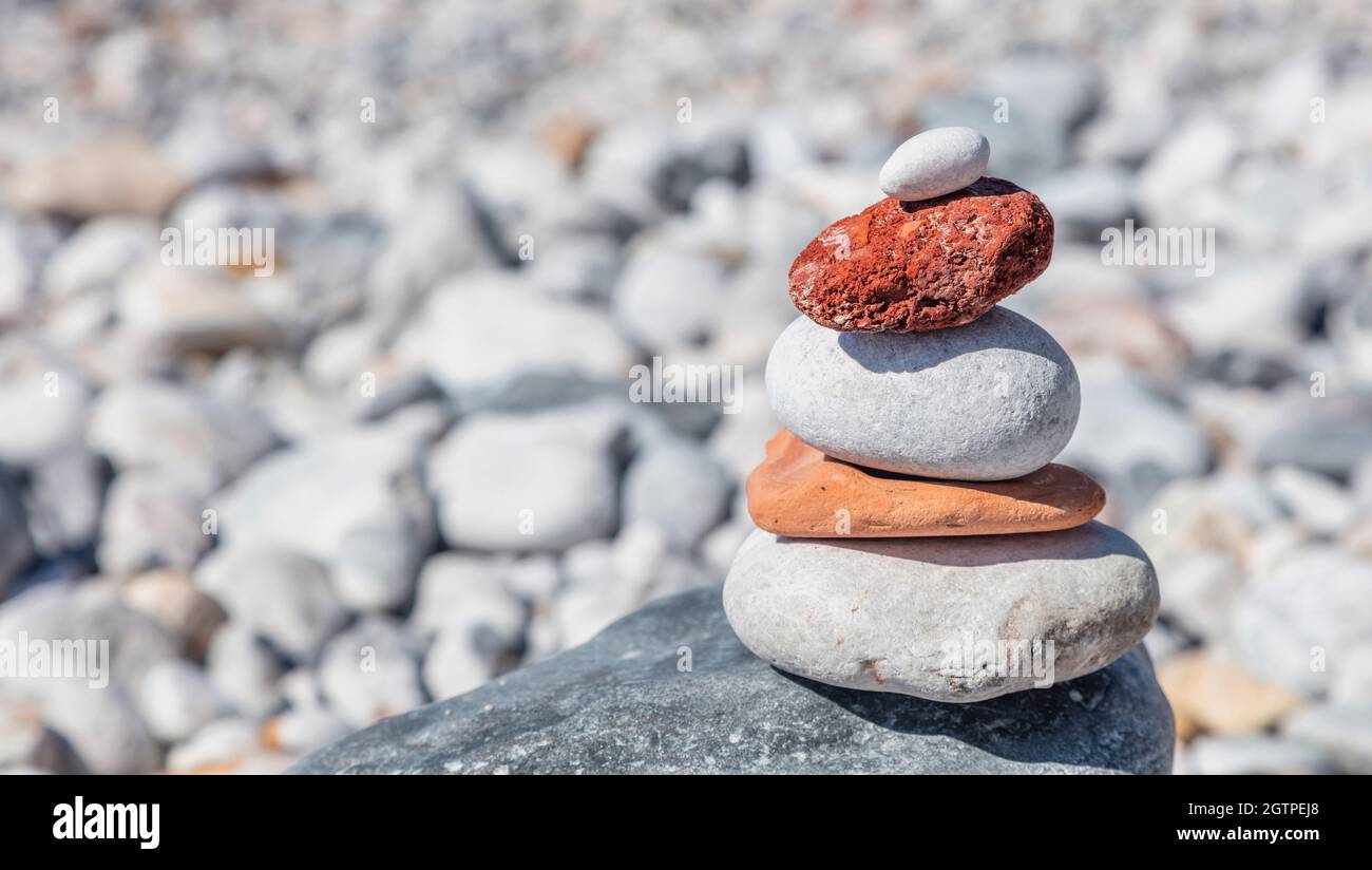 Pietre di equilibrio Zen, torre di roccia liscia impilata su sfondo di spiaggia di ghiaia, giorno di sole. Concetto di armonia e pace, spazio di copia, modello Foto Stock