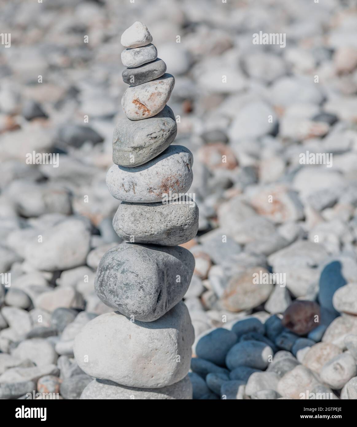 Pietre di Zen, torre di roccia liscia impilata su sfondo di spiaggia di ciottoli, giorno di sole. Equilibrio, armonia e concetto di pace. Feng shui, yoga, terapia naturale Foto Stock