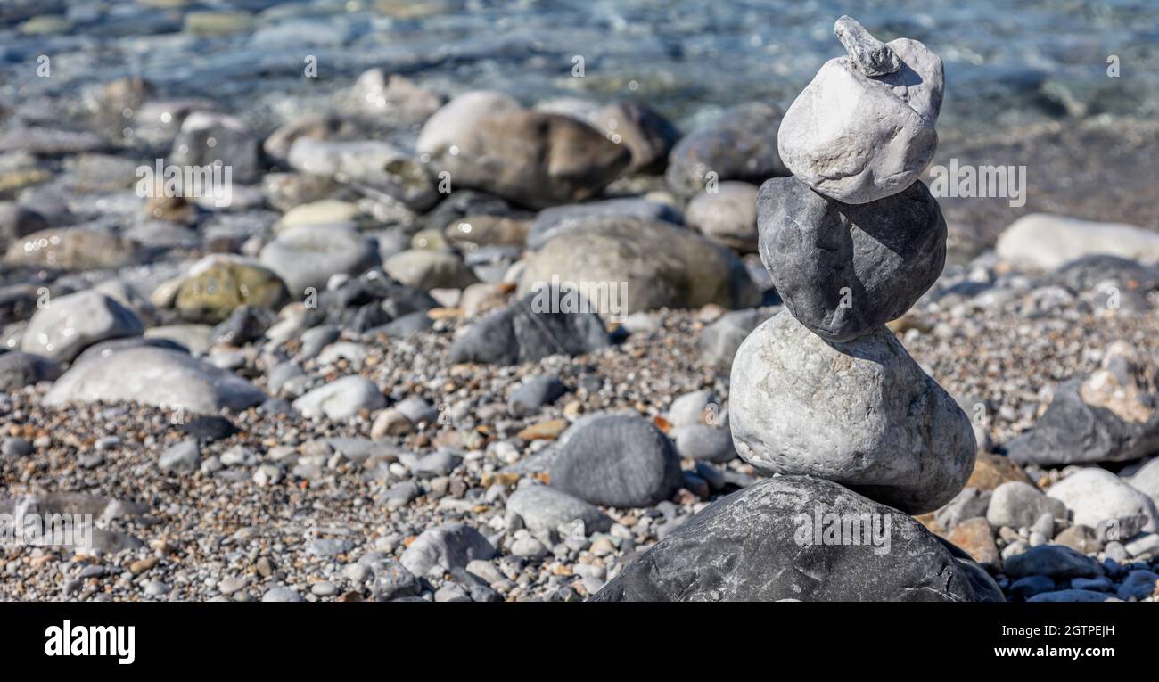 Equilibrio, pietre zen, torre di roccia impilata su spiaggia di ciottoli, sfondo blu mare, giorno di sole. Feng shui, armonia e concetto di pace. Spazio di copia, modello. Foto Stock