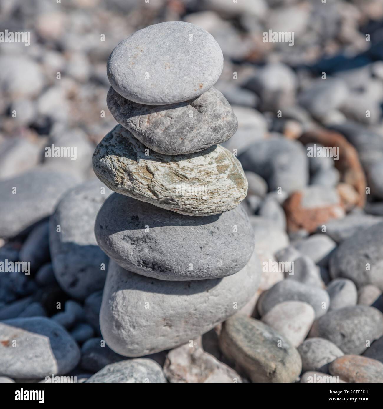 Equilibrio, armonia e concetto di pace. Pietre di Zen, torre di roccia liscia impilata su sfondo di spiaggia di ciottoli, giorno di sole. Feng shui, yoga, terapia naturale Foto Stock