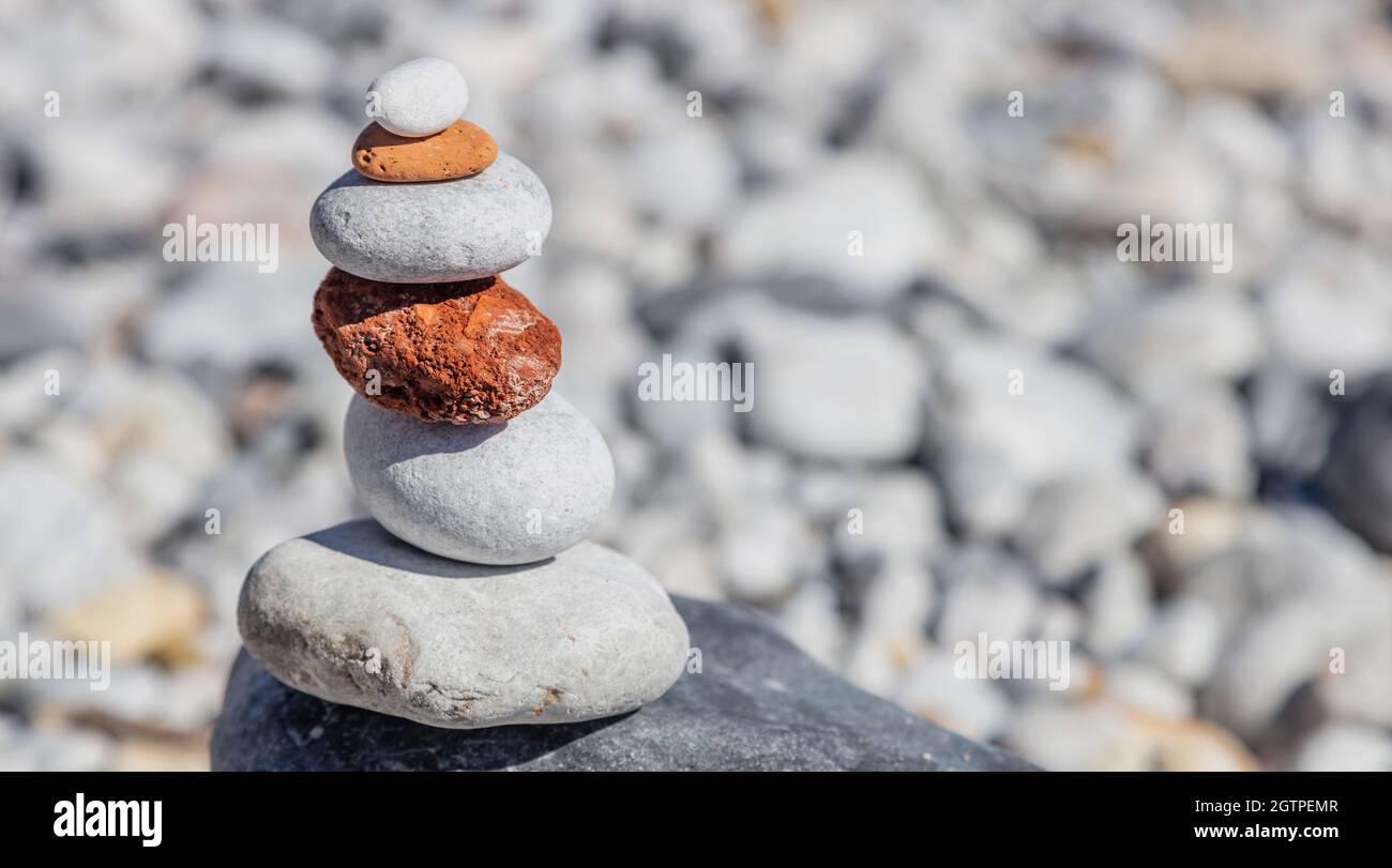 Pietre di equilibrio Zen, torre di roccia liscia impilata su sfondo di spiaggia di ghiaia, giorno di sole. Concetto di armonia e pace, spazio di copia, modello Foto Stock