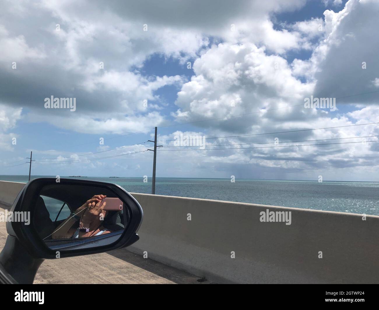 Riflesso della persona sullo specchio retrovisore laterale contro il cielo Foto Stock