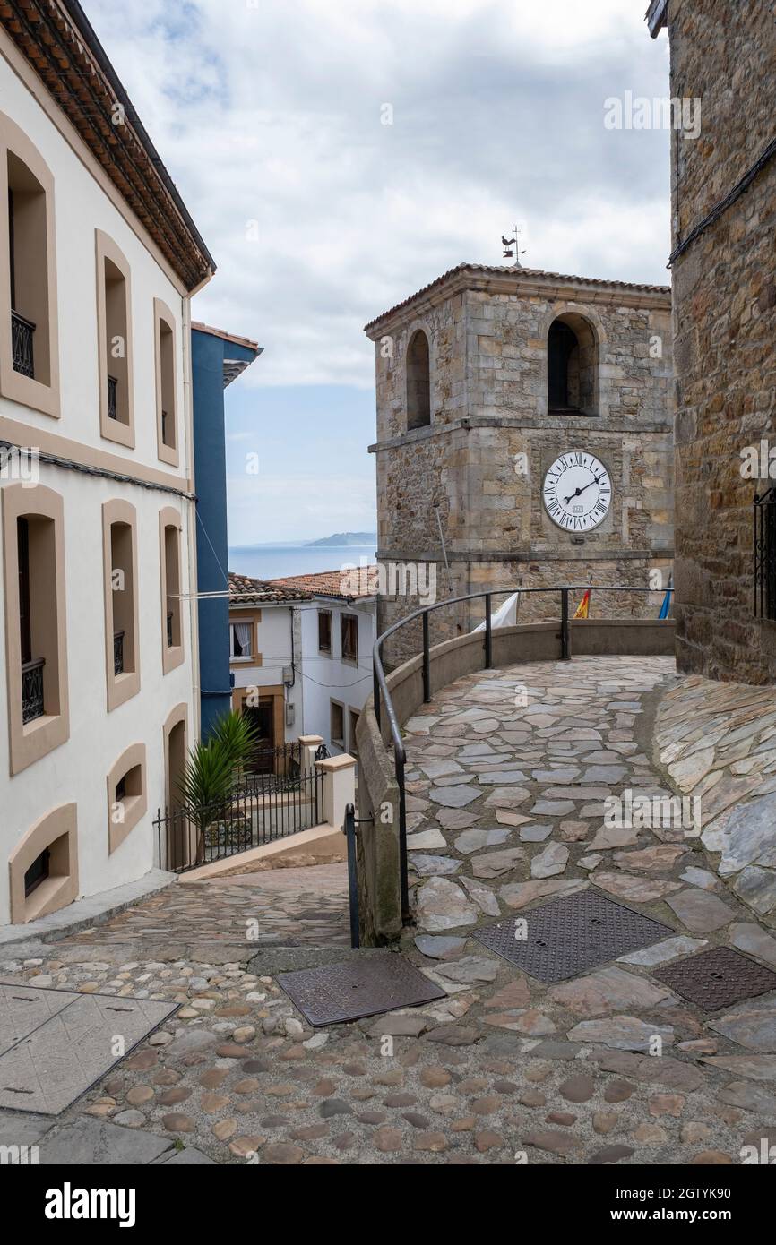 Strade strette del villaggio di pescatori di Lastres, Asturie, Spagna, con la torre dell'orologio del municipio, con il mare Cantabrico sullo sfondo, v Foto Stock