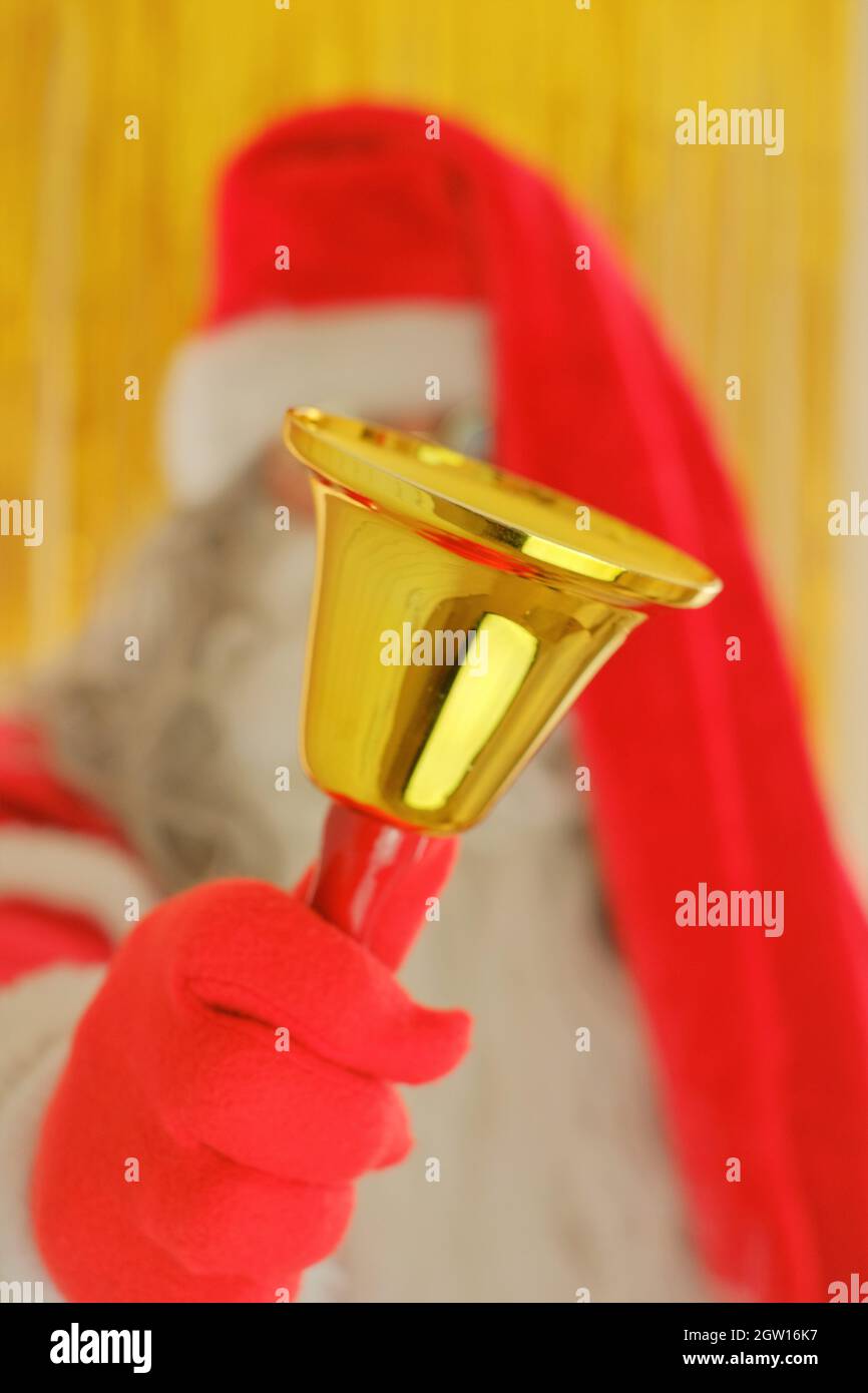 Stagione di Natale. Babbo Natale con campana dorata su sfondo dorato sfocato. Buon Natale. Foto Stock