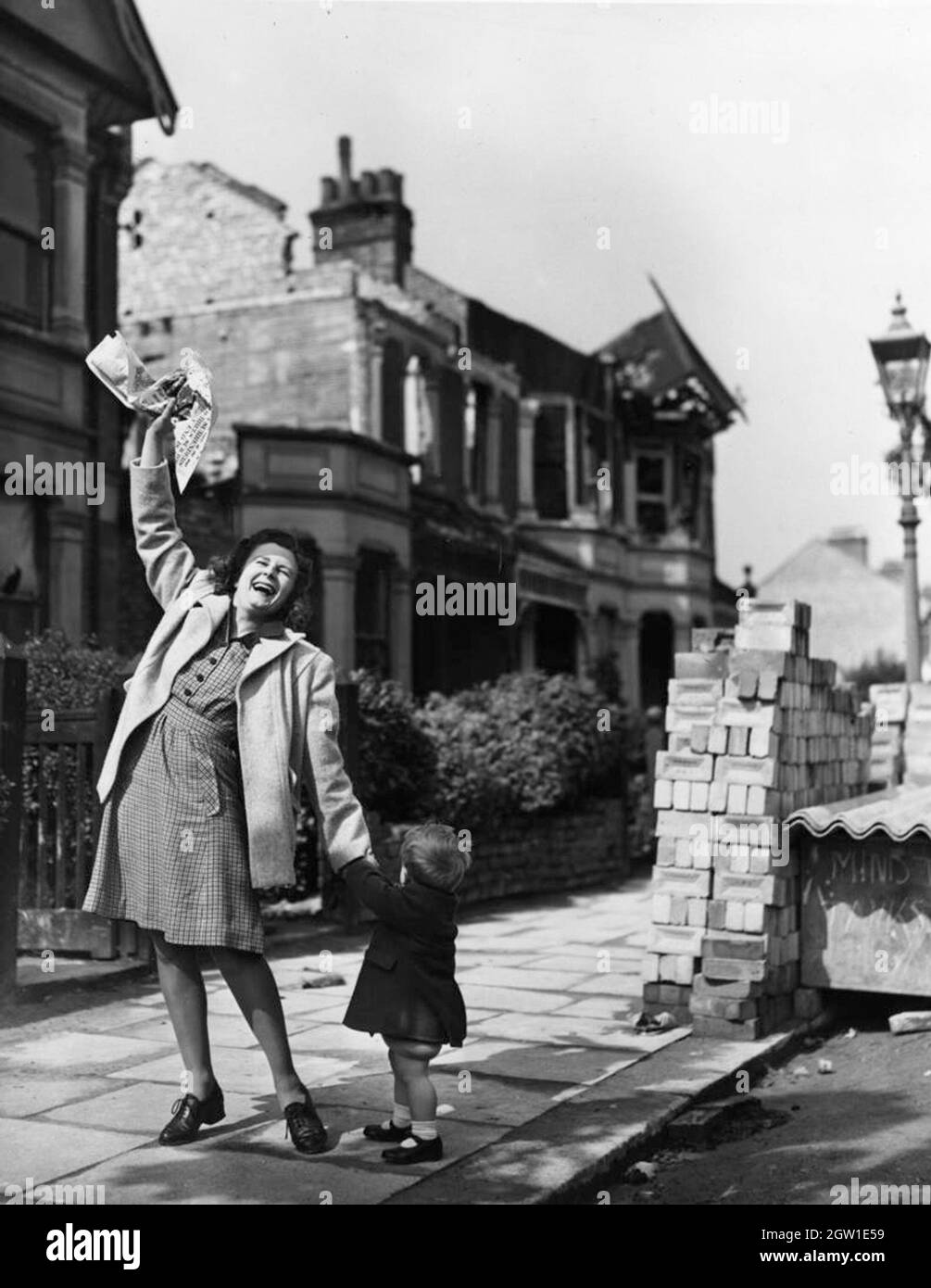 Una donna con un bambino giovane che gaudì per strada il giorno della Ve (Giornata della Vittoria in Europa), l'8 maggio 1945 Foto Stock