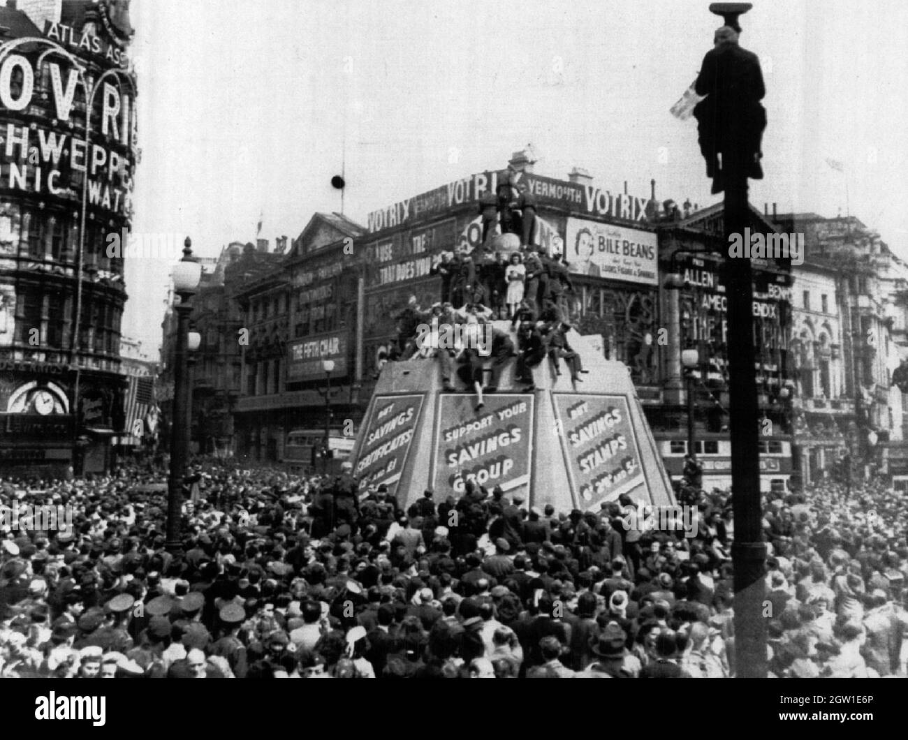 La folla riempie il Piccadilly Circus di Londra durante la celebrazione del V-e Day 8 maggio 1945. Alcuni posate in cima alla Statua di Eros e una persona ha salito un posto. Foto Stock