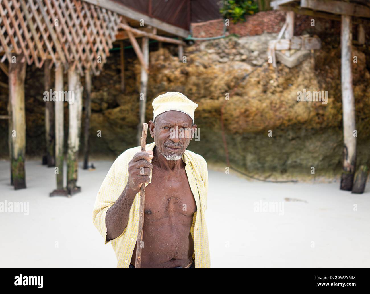 shepard africano invecchiato camminando sulla spiaggia tenendo bastone Foto Stock