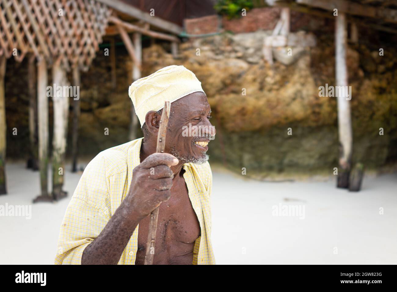 shepard africano invecchiato camminando sulla spiaggia tenendo bastone Foto Stock