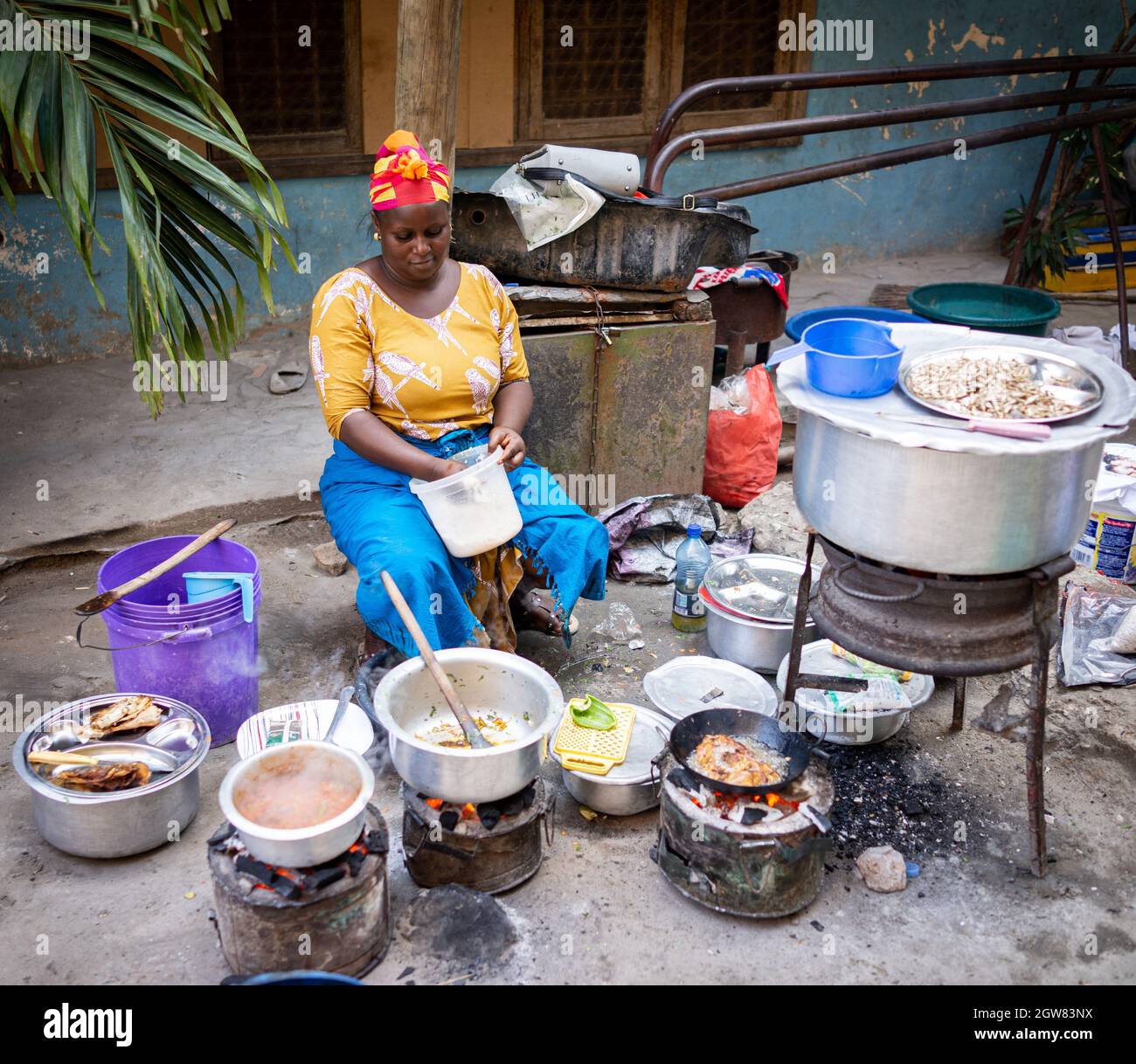 Donna africana che cucina cibo tradizionale in strada Foto Stock