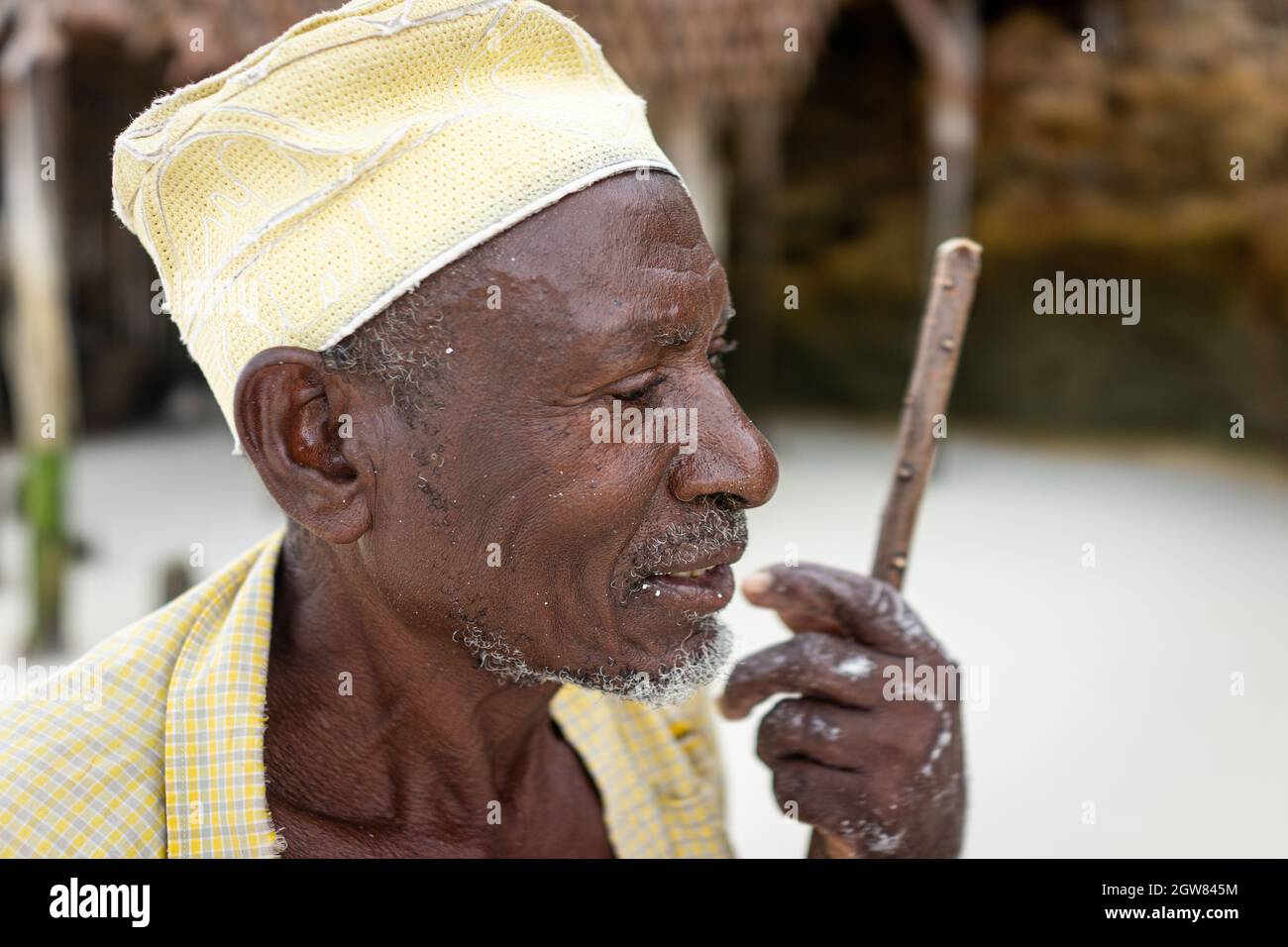 shepard africano invecchiato camminando sulla spiaggia tenendo bastone Foto Stock