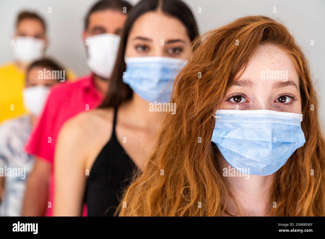 Gruppo di persone in attesa in coda con maschera protettiva in distanza sociale. Pandemia e concetto di assistenza sanitaria. Foto di alta qualità Foto Stock
