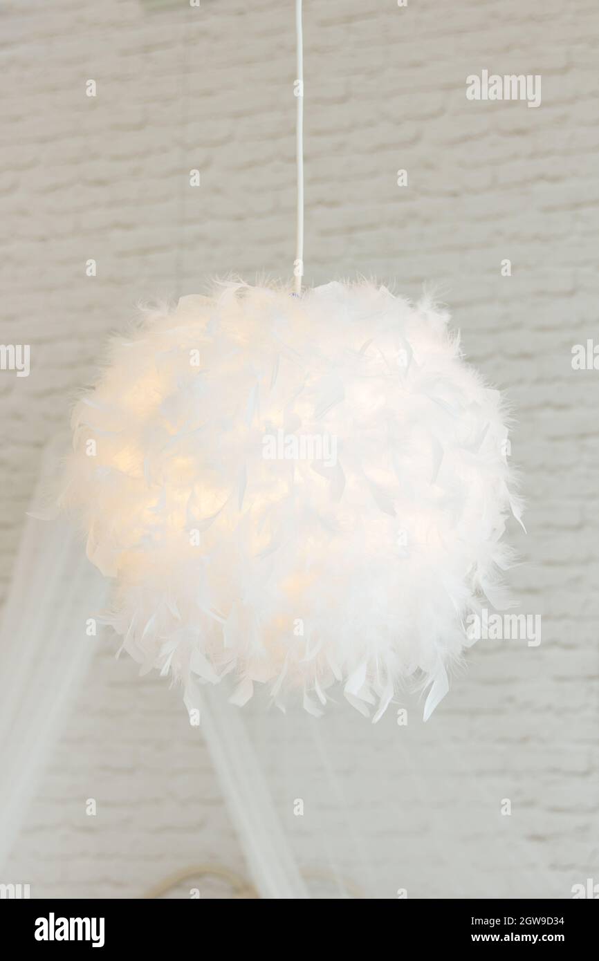 Moderna lampada con abajur di piume bianche, dà luce romantica in camera da letto Foto Stock