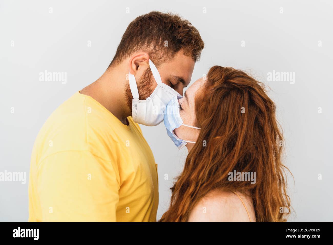 Una coppia ama e perde eachother e cercando di baciare con maschera di protazione medica. Assistenza sanitaria e pandemia. Foto di alta qualità Foto Stock