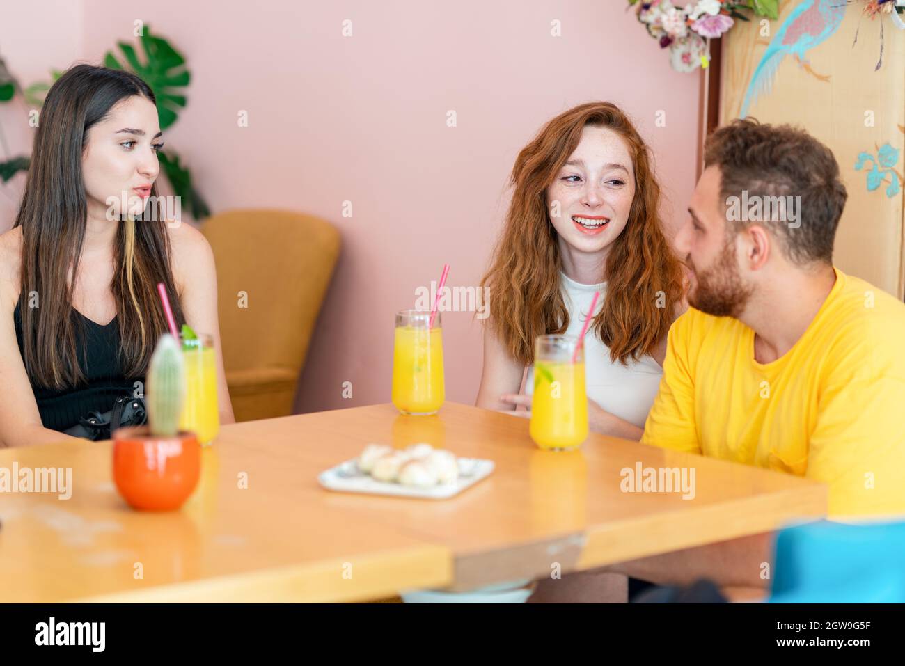 Gruppo di amici che chiacchierano e sorridono mentre si siedono e bevono una bevanda in un caffè. Foto di alta qualità Foto Stock