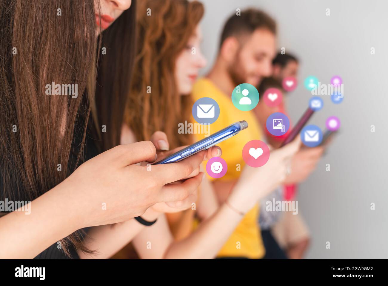 Gruppo di amici in piedi e guardando al loro cellulare. Social media e concetto di dipendenza tecnologica. Foto di alta qualità Foto Stock