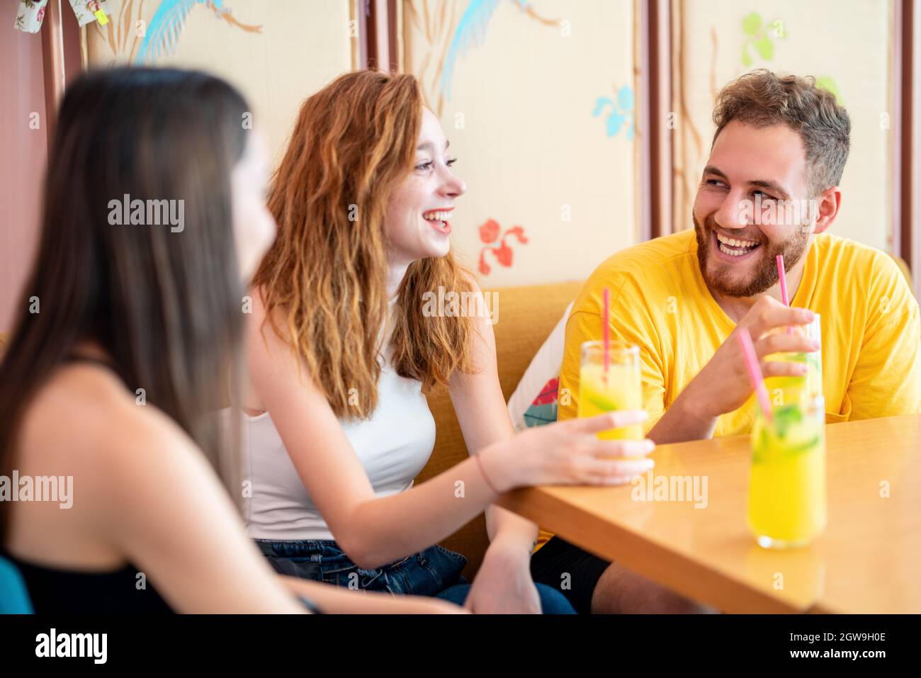 Gruppo di amici che chiacchierano e sorridono mentre si siedono e bevono una bevanda in un caffè. Foto di alta qualità Foto Stock