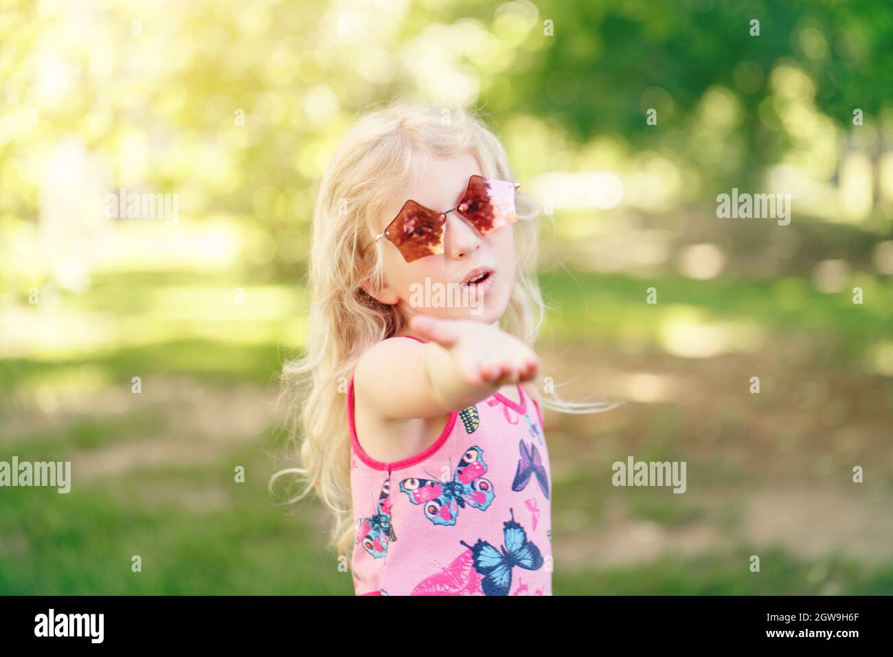 Giovane ragazza in posa in Fancy Pink a forma di pentagonale occhiali da  sole all'aperto. Carino adorabile Child elegante Foto stock - Alamy
