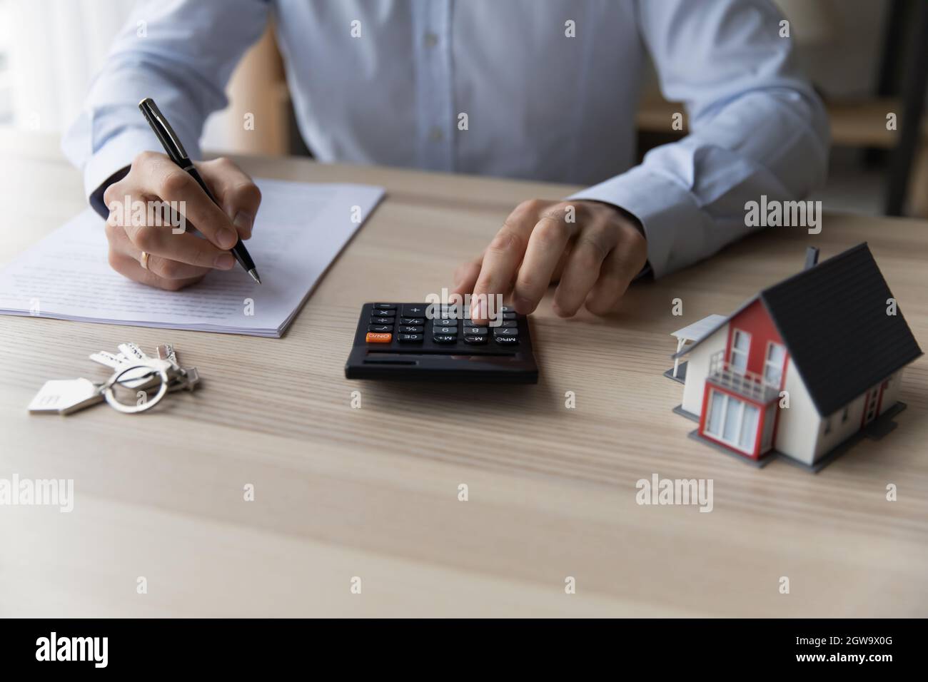 Realtor businessman usando calcolatore, seduto alla scrivania con mockup casa Foto Stock