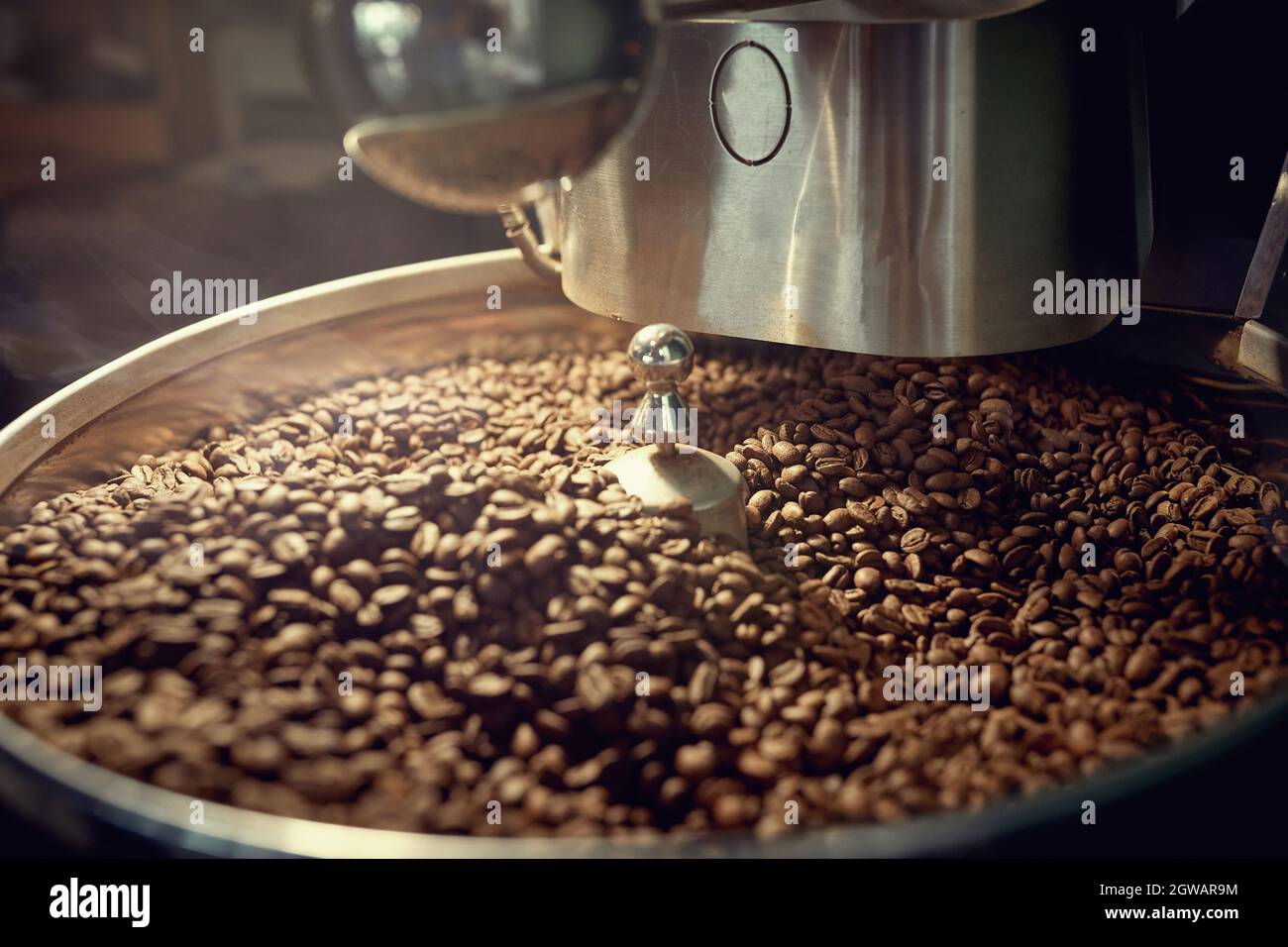 Chicchi di caffè freschi che tostano in macchina. Chicchi di caffè che tostano Foto Stock