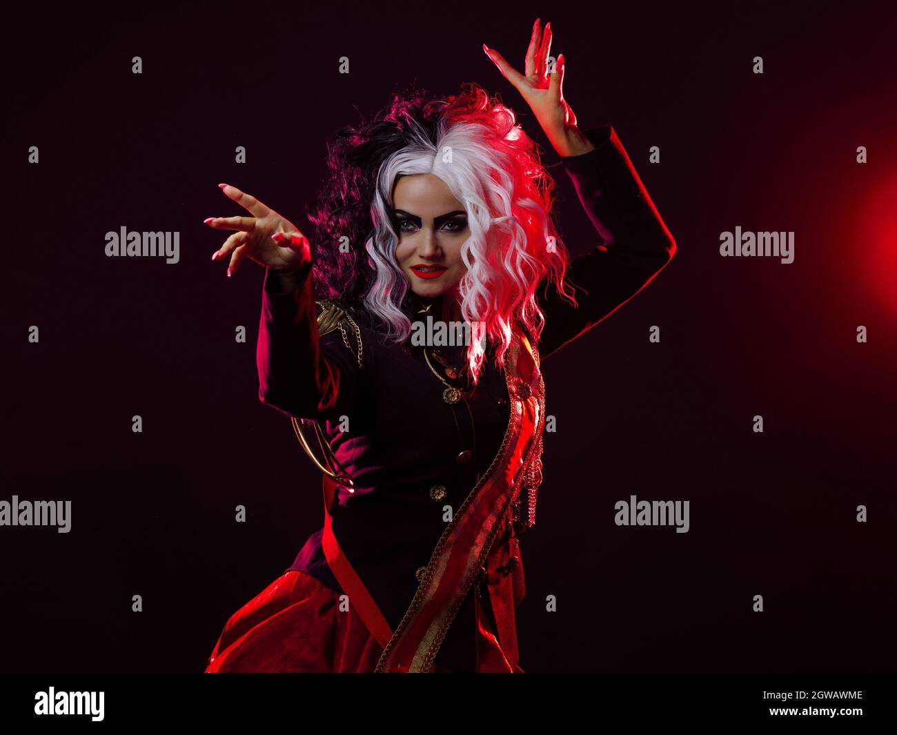 Una donna luminosa e scioccante con un acconciatura in bianco e nero è vestita in una divisa decorata e una gonna piena. Retroilluminazione rossa sul retro. Balli accesi Foto Stock
