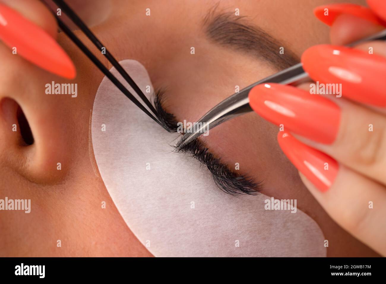 Mani del cosmetologo che usano le pinzette per applicare le ciglia false Foto Stock