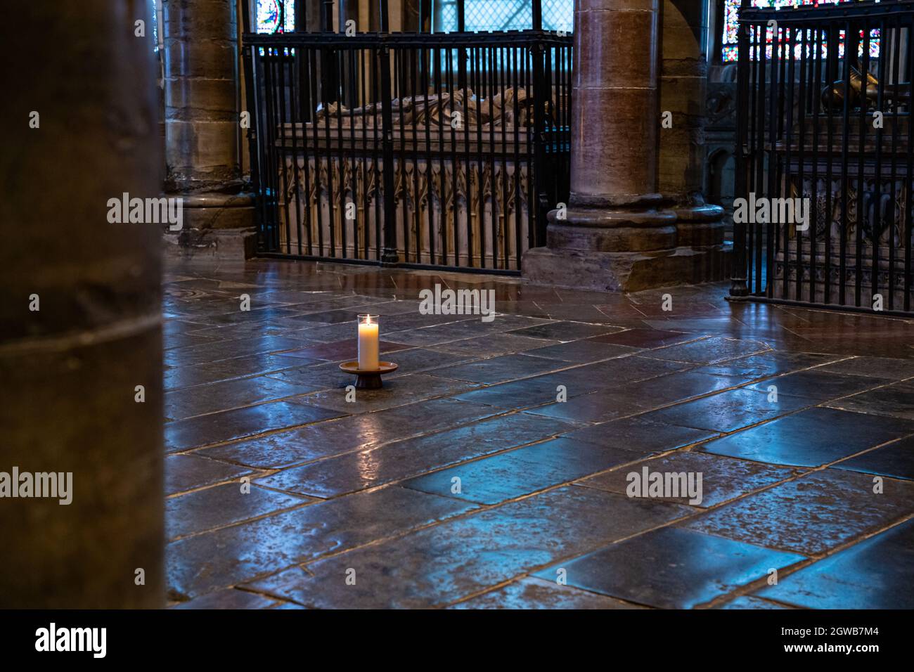 Candela solitaria illuminata su un antico pavimento in pietra all'interno della storica cattedrale Foto Stock