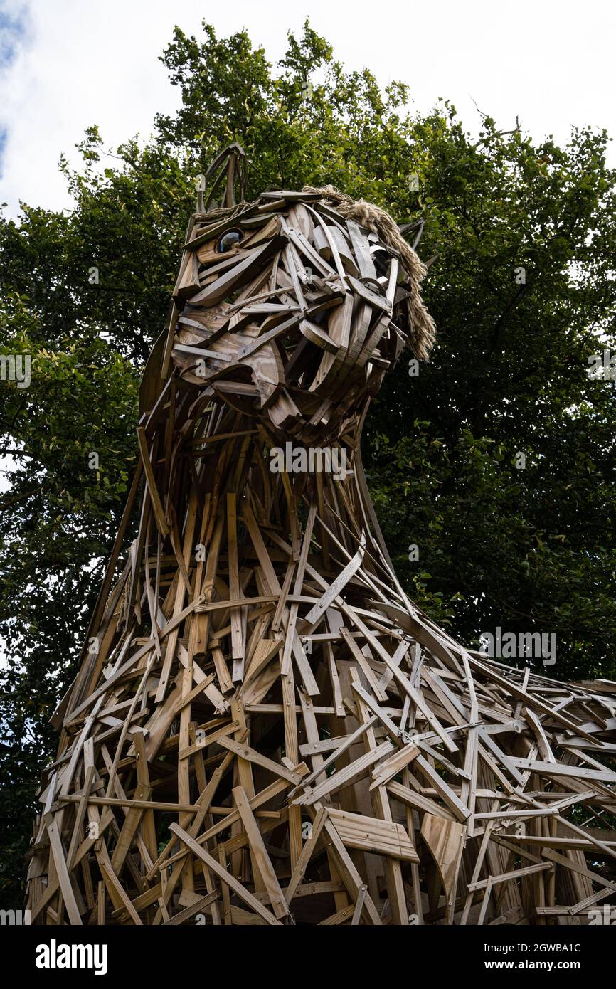 Spettacolare scultura in legno della testa di leone gigante realizzata con strisce di legno contro alberi verdi Foto Stock