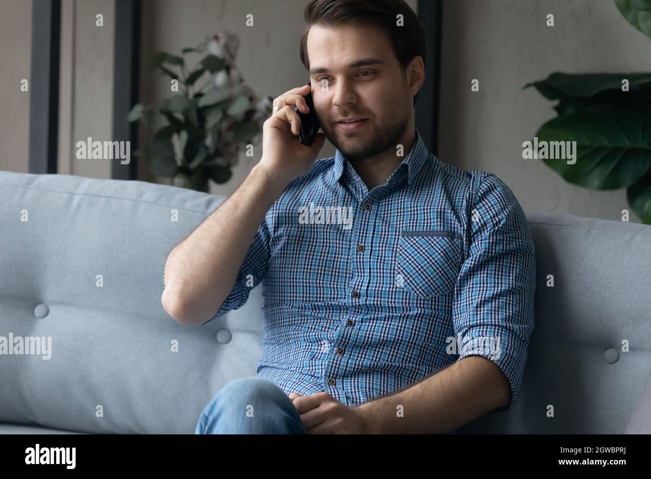 Un uomo sorridente che parla al telefono e che si diverti a conversare con piacere Foto Stock