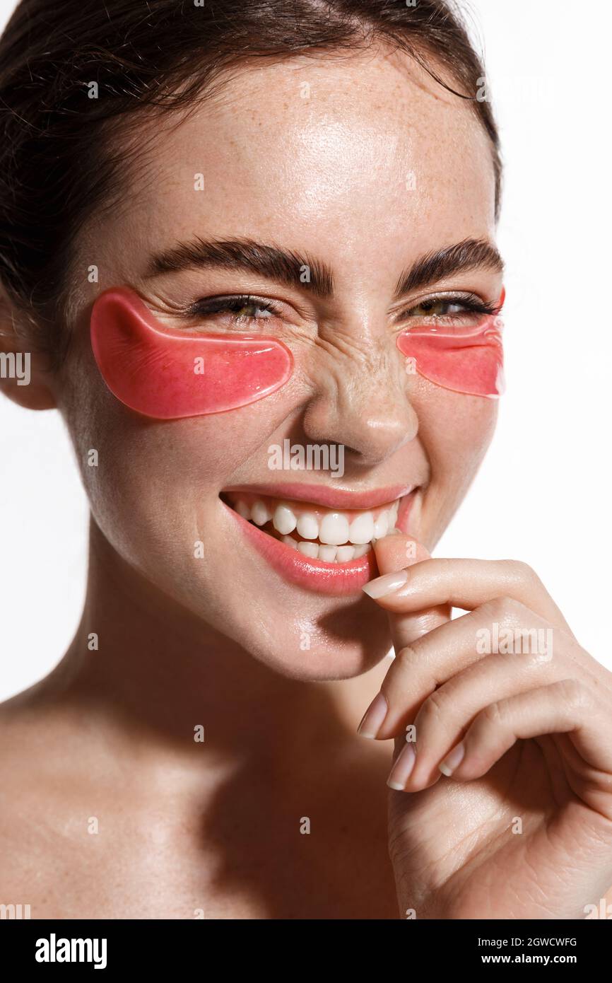 Ritratto verticale di donna che indossa sotto gli occhi cerotti rosa,  collagene prodotto per la cura della pelle per ringiovanimento e viso  luminoso sano, sorridente felice a Foto stock - Alamy