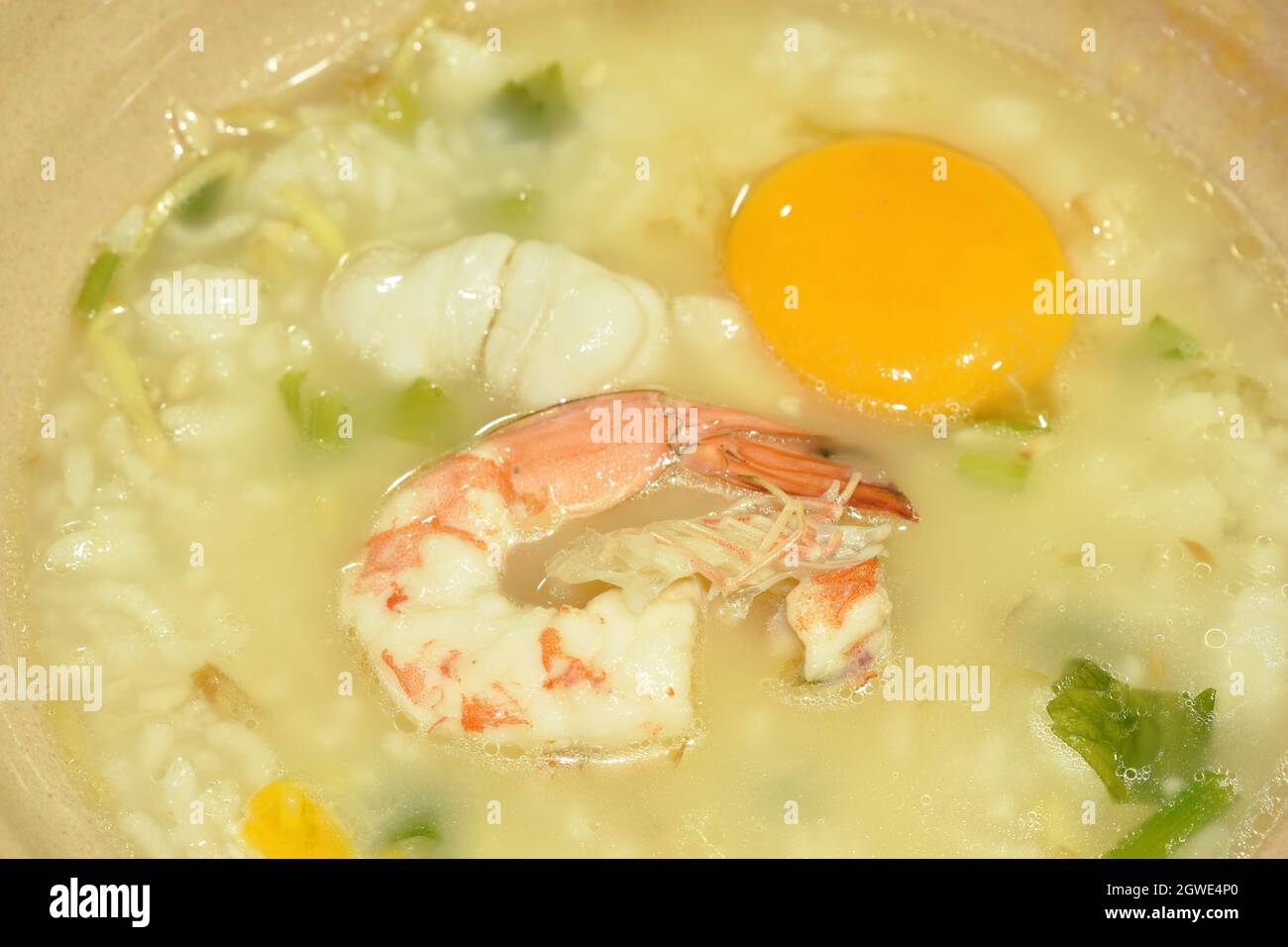 gamberetti di porridge di riso e calamari con tuorlo d'uovo con aggiunta di zenzero sulla ciotola Foto Stock