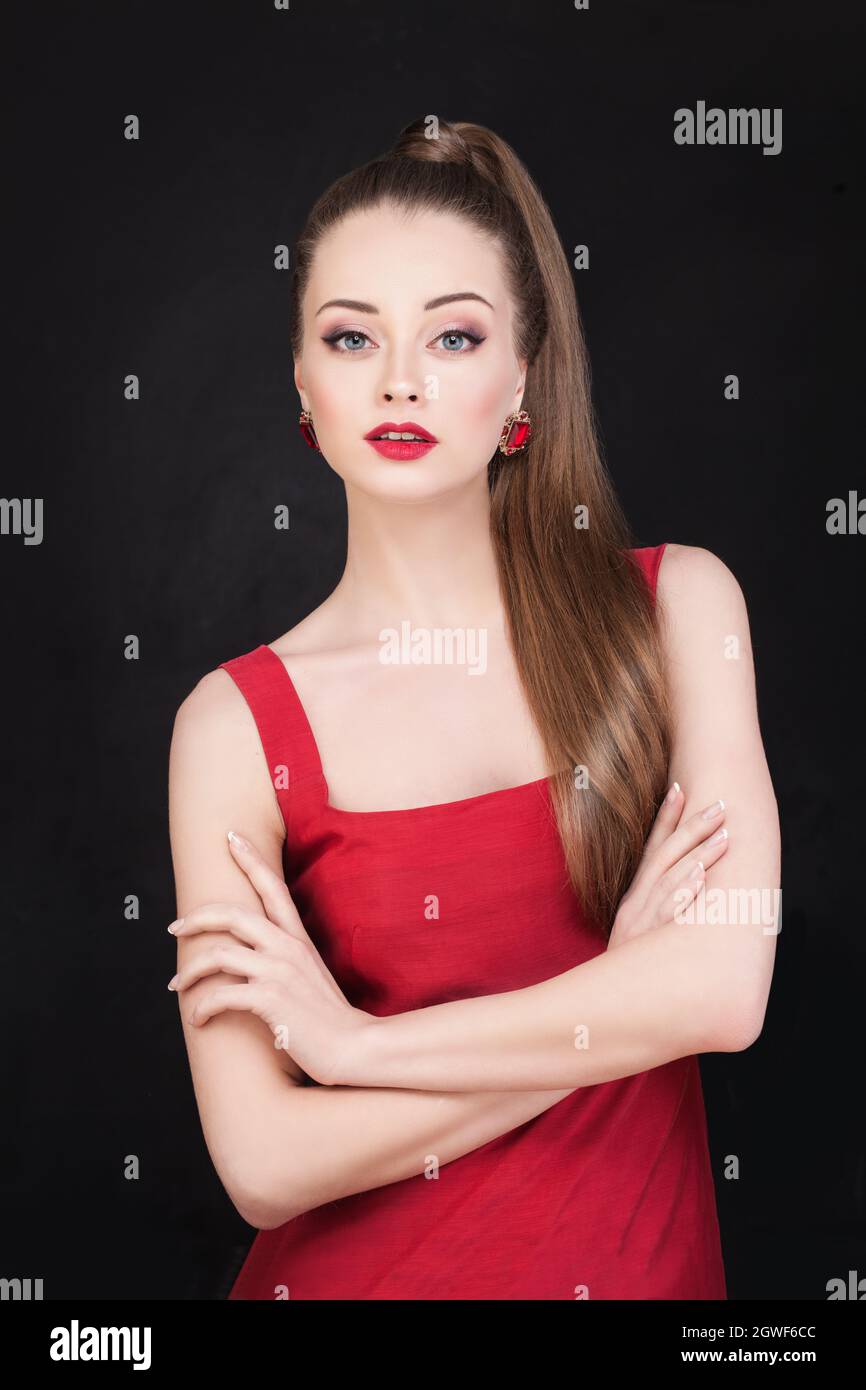 Modello donna di moda piuttosto elegante in orecchini dorati e abito rosso nero Foto Stock