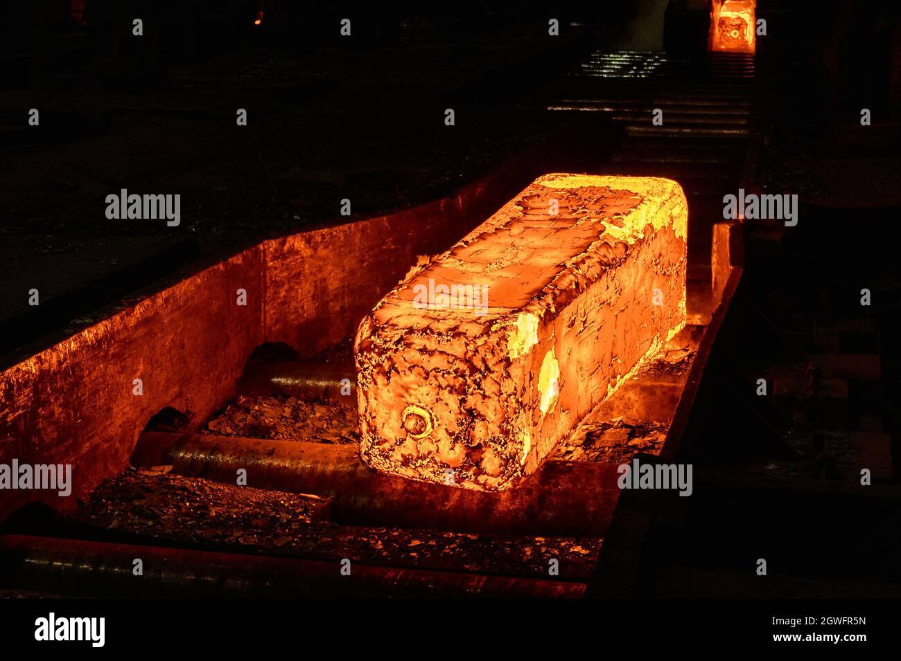 Billetta di metallo rosso-caldo sul tavolo a rulli di un laminatoio Foto Stock