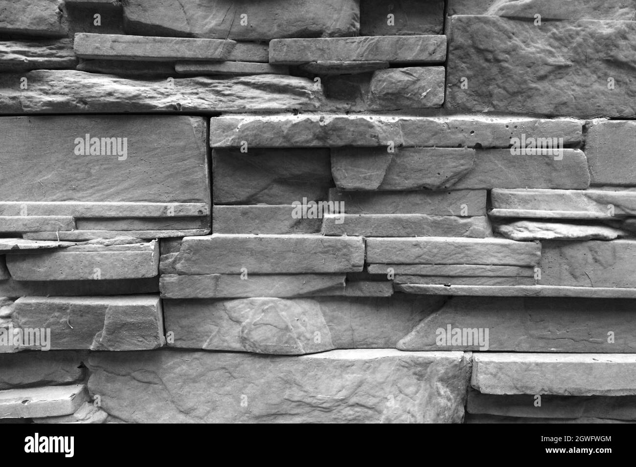 Immagine di una parete composta da mattoni grigi di diverse dimensioni che sono impilati orizzontalmente che decorano una parete esterna di un edificio Foto Stock