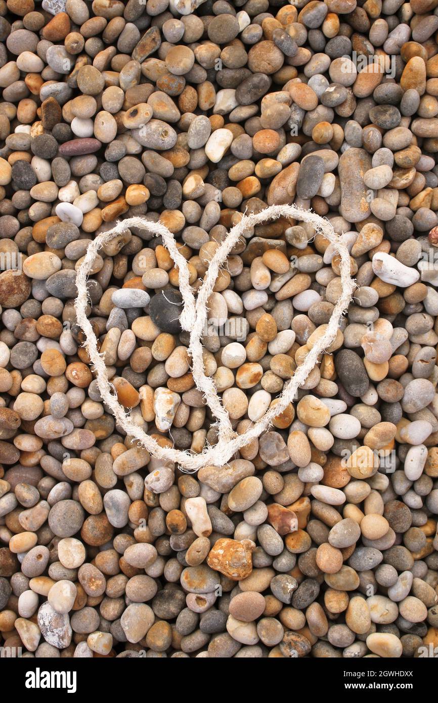 corda cuore sulla spiaggia di pietre Foto Stock