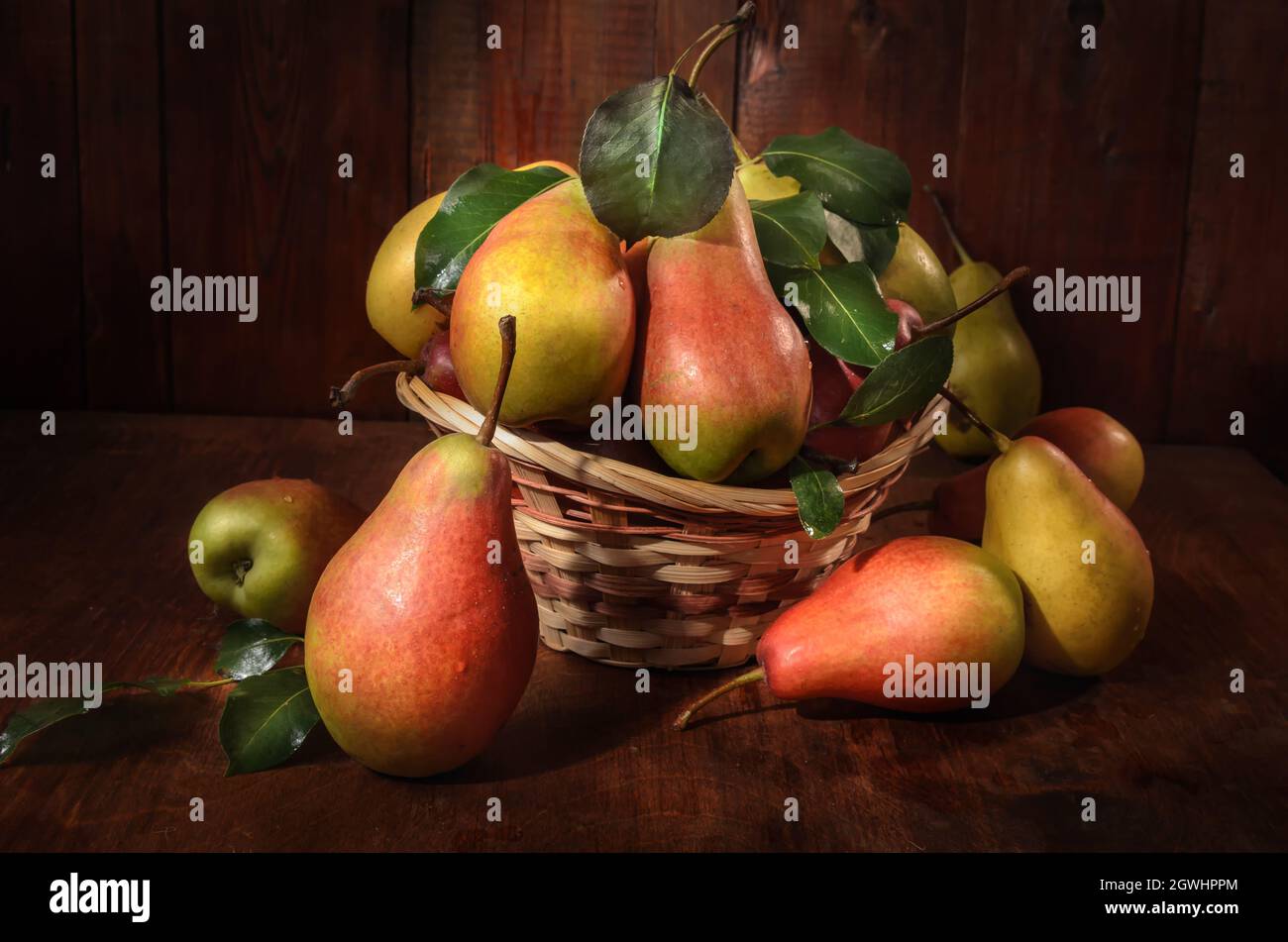pere in un cestino su sfondo di legno scuro in stile rustico Foto Stock