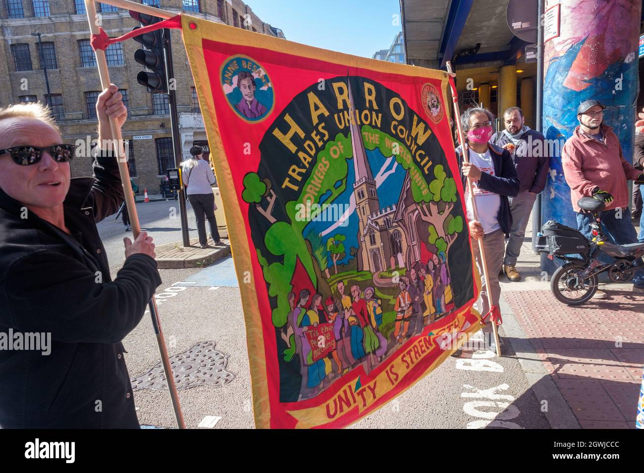 Londra, Regno Unito. 3 ottobre 2021. Harrow Trades Union Banner. Le persone si riuniscono nell'85° anniversario della Battaglia di Cable St per ricordare l'atto di unità contro la minaccia fascista quando le comunità ebraiche e irlandesi di East London e i loro alleati hanno bloccato le strade per impedire che Oswald Mosley e la sua Unione britannica dei fascisti marciassero. Marciarono da Dock St lungo Cable St ad un raduno accanto al murale in St George's Gardens. Peter Marshall/Alamy Live News Foto Stock