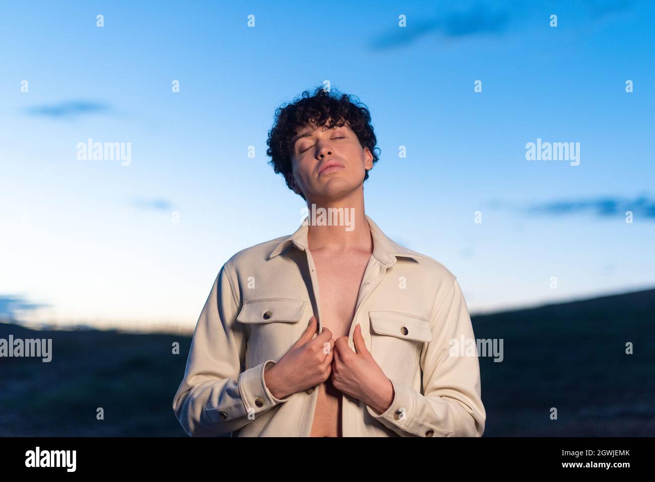 Ritratto durante il crepuscolo di un maschio non binario che posa rilassato Foto Stock