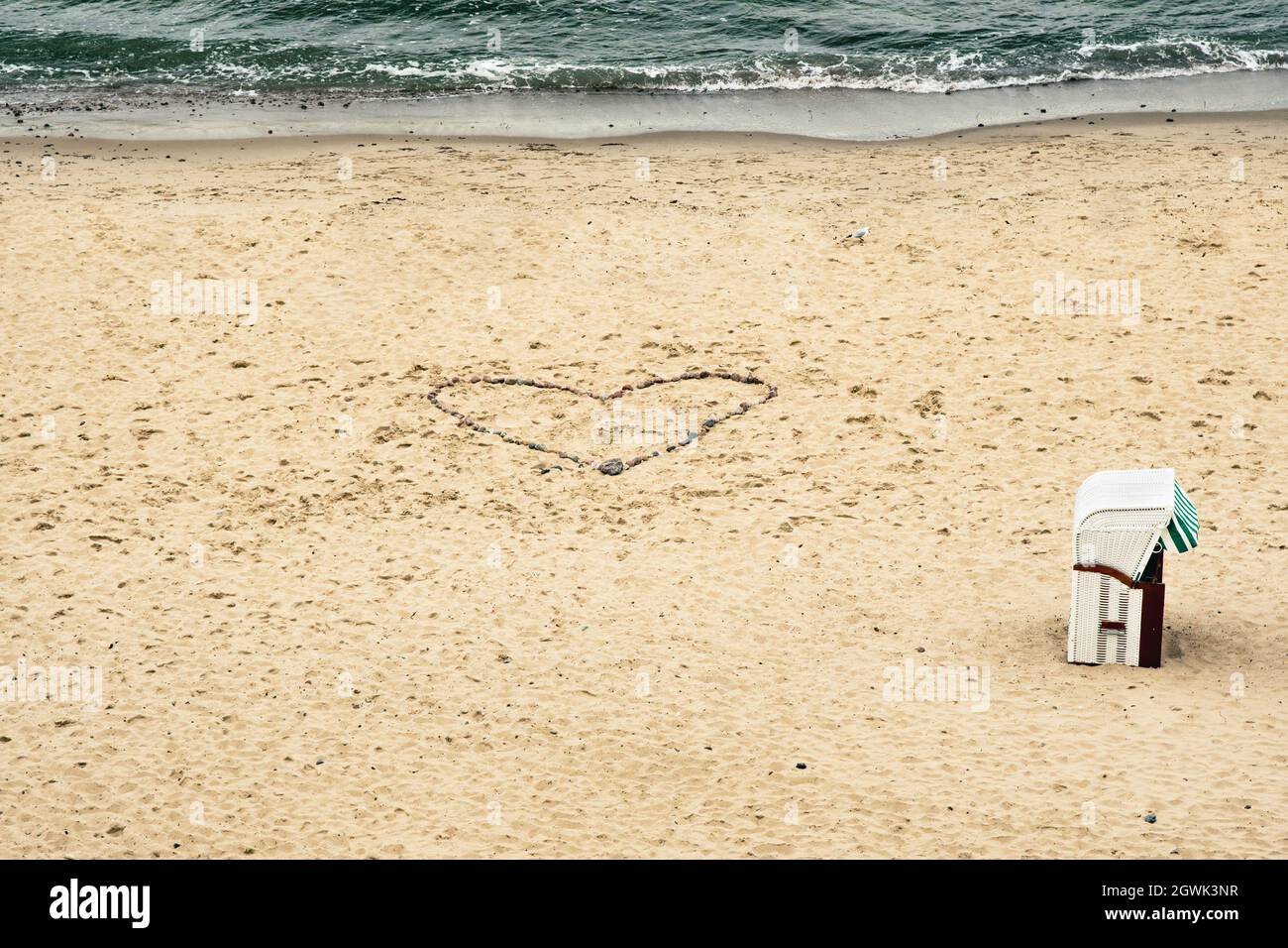 cuore segnato nella sabbia con una sedia da spiaggia Foto Stock