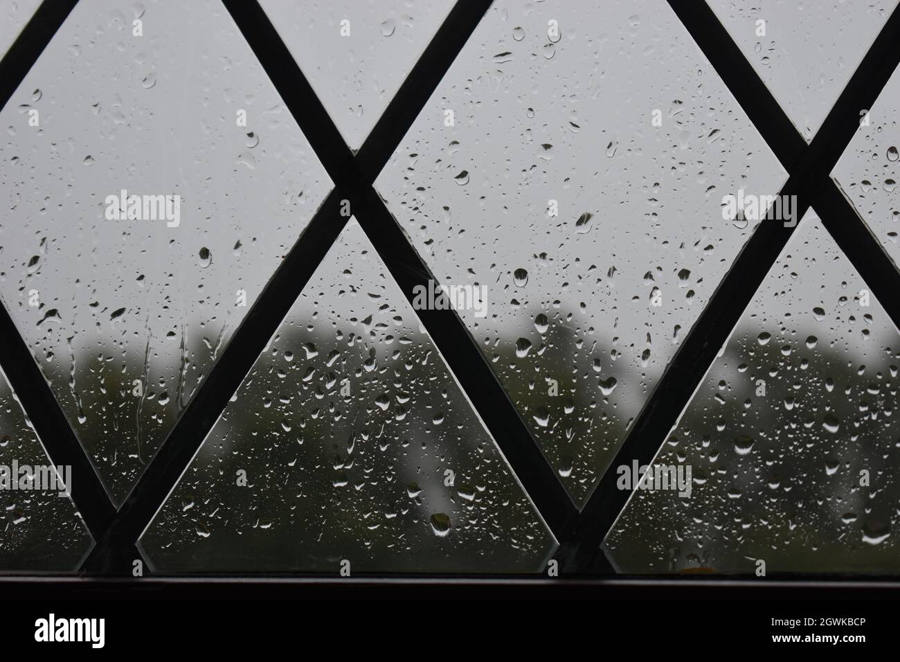 Gocce di pioggia su una finestra a forma di triangolo. Foto Stock