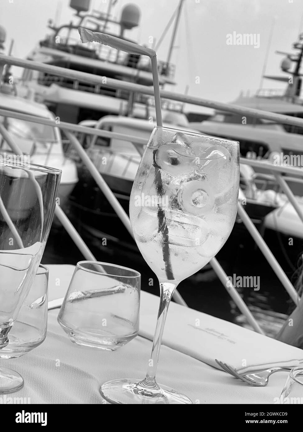 Una foto in scala di grigi di una bevanda fredda con una cannuccia in un bicchiere sul tavolo dello yacht Foto Stock