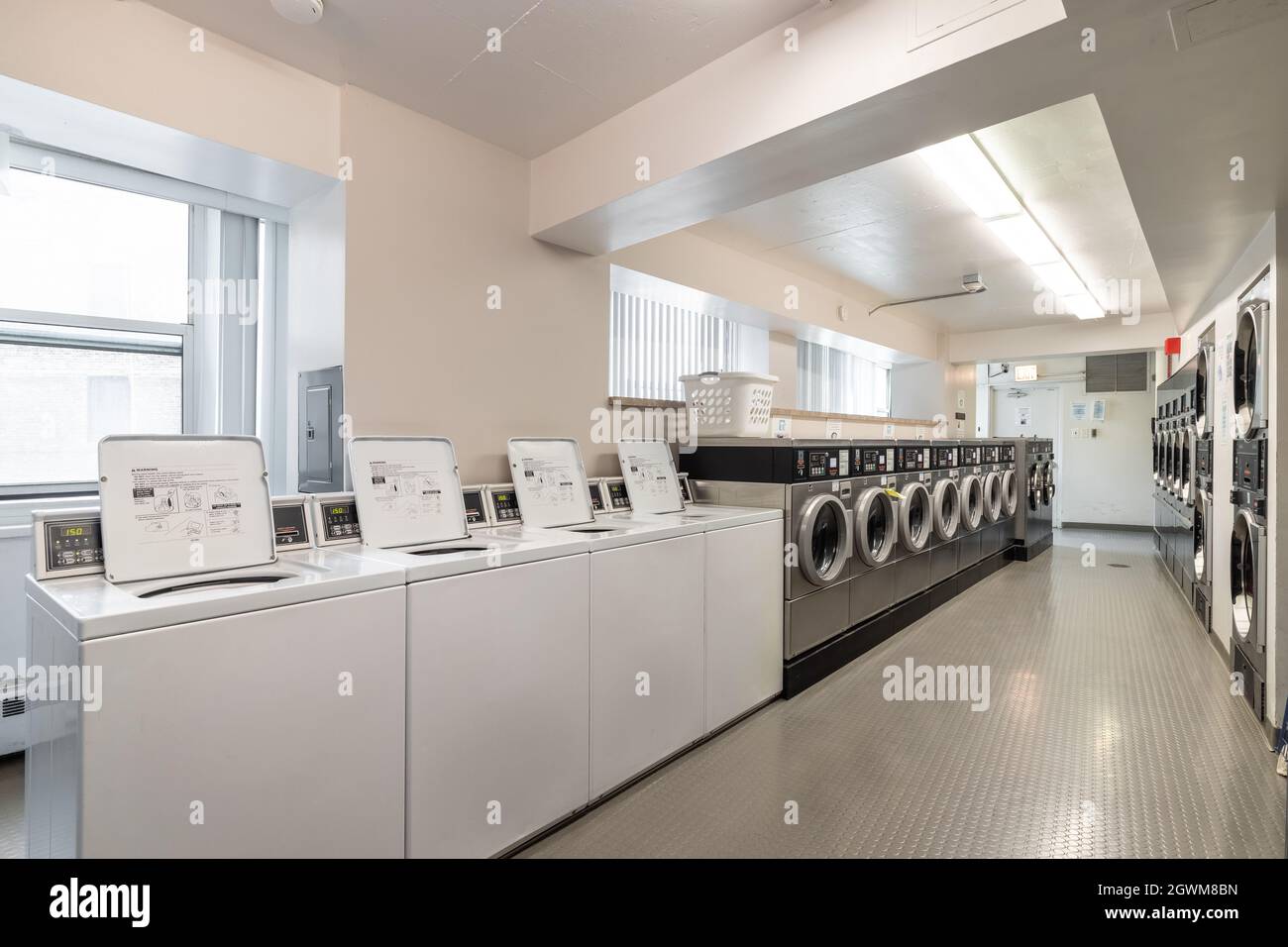 Un'alta lavanderia in centro citta' con lavatrici e asciugatrici a carico frontale Speed Queen allineate in file. Foto Stock