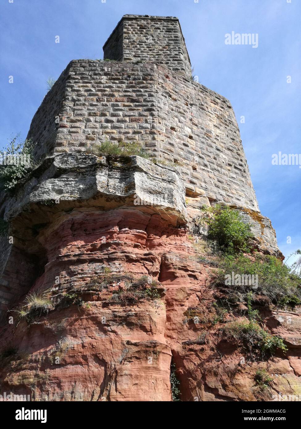 Un'immagine ad angolo basso di un antico edificio in pietra costruito su rocce sotto un cielo blu senza nuvole Foto Stock